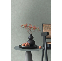 Scène d''intérieur décorative avec une petite table, un vase avec des fleurs et une chaise devant un mur texturé.