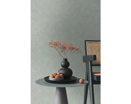 Scène d''intérieur décorative avec une petite table, un vase avec des fleurs et une chaise devant un mur texturé.