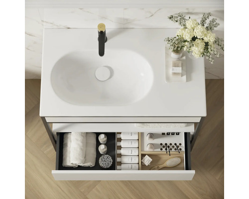 Meuble-lavabo avec tiroir ouvert, comprenant des serviettes et des accessoires de salle de bain