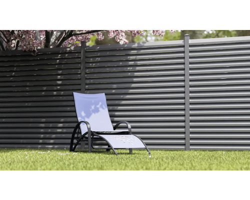 Scène de jardin avec chaise longue devant une clôture à lamelles