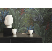 Dekoratives Zimmer mit botanischer Tapete, Skulptur, Pflanze und Stift auf einem dunklen Tisch.