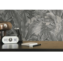 Nahaufnahme eines Schreibtisches mit tropischer Blättertapete, einer Lampe, einem Kalender, Stiften und einem Notizbuch