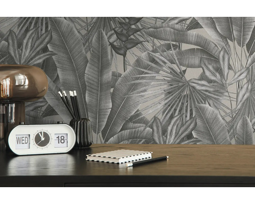 Nahaufnahme eines Schreibtisches mit tropischer Blättertapete, einer Lampe, einem Kalender, Stiften und einem Notizbuch