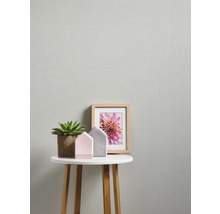 Nahaufnahme einer dezent gemusterten Tapete mit Tisch, Pflanze, Hausdeko und Bilderrahmen