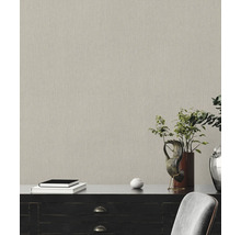 Nahaufnahme einer strukturierten Tapete in einem Raum mit Kommode, Büchern und Pflanzendekoration