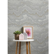 Wohnraum mit gemusterter Tapete, Tisch, Pflanze und Bilderrahmen