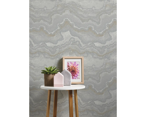 Wohnraum mit gemusterter Tapete, Tisch, Pflanze und Bilderrahmen