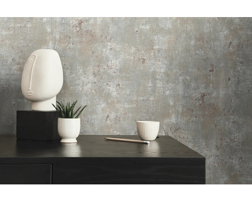 Nahaufnahme einer grauen Betonstruktur-Tapete mit minimalistischer Dekoration auf einem schwarzen Sideboard.