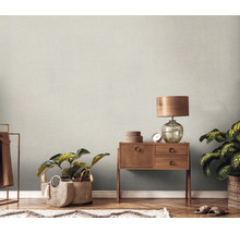 Szene mit einer Holzkommode, einer Lampe, Zimmerpflanzen und einer strukturierten Tapete