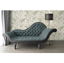 Chaiselongue mit Knopfheftung vor floral gemusterter Tapete und Stehlampe