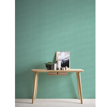 Helles Zimmer mit Uni-Tapete, Tisch, Pflanze und Dekorationsartikeln.