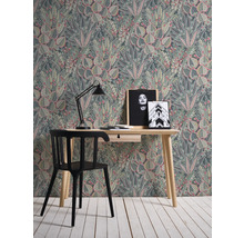 Ein Zimmer mit einem Schreibtisch, einem Stuhl und einer Tapete mit Pflanzenmuster.