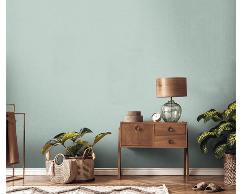 Wohnzimmer mit Holzboden, Kommode, Lampe, Pflanzen und Teppich