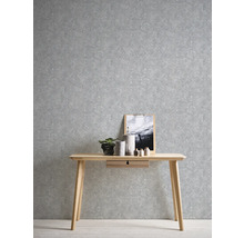 Szene mit einem Schreibtisch aus Holz vor einer grauen gemusterten Tapete.