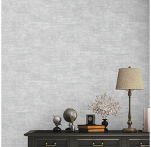 Nahaufnahme einer Wand mit einer grauen Textiltapete, die eine subtile Textur aufweist.