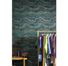 Wohnszene mit einer grünen Vliestapete mit wellenförmigem Muster, Kleiderständer und Accessoires