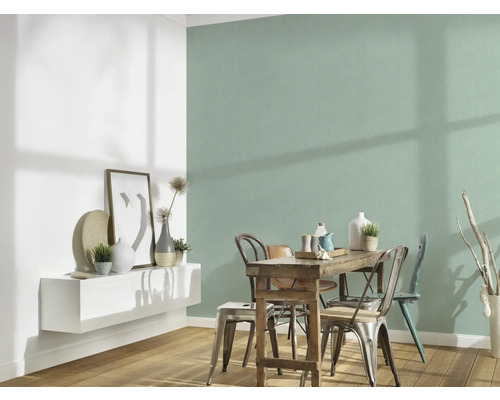 Esszimmer mit Holztisch und Stühlen vor mintgrüner Wand