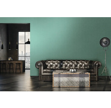 Wohnzimmer mit Ledersofa, Couchtisch und Stehlampe vor einer Wand mit grüner Tapete