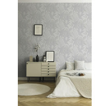 Helles Schlafzimmer mit gemusterter Tapete, Kommode, Bett und rundem Teppich