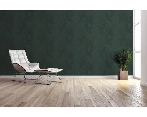 Wohnraum mit grüner Blättertapete, Sessel, Fusshocker, Topfpflanze und Holzboden