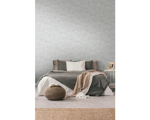 Schlafzimmer mit Bett, Nachttisch und hellgrauer Tapete