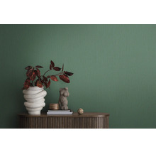 Scène d''intérieur décorative avec plante dans un vase sculptural, buste de femme et deux livres sur un meuble marron devant un papier peint vert