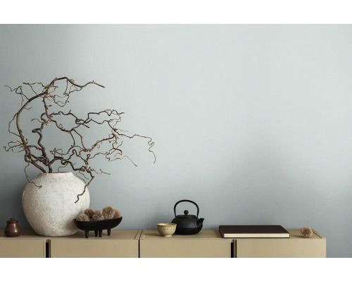 Branches décoratives dans un vase à côté d''une théière sur un buffet