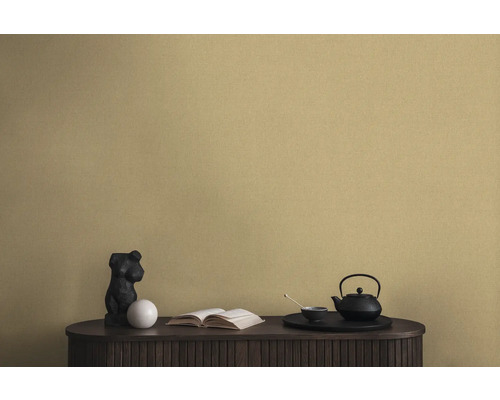 Scène décorative avec une théière noire, une statue et un livre sur une armoire devant un papier peint mural
