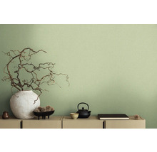 Scène décorative avec vase, branches, théière et autres éléments décoratifs sur une commode devant un mur