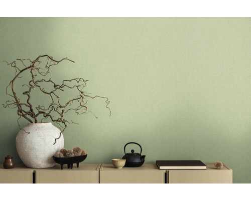 Scène décorative avec vase, branches, théière et autres éléments décoratifs sur une commode devant un mur