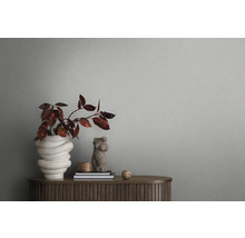 Nature morte décorative avec un vase de fleurs, des livres et un buste féminin sur une armoire en bois devant un mur gris