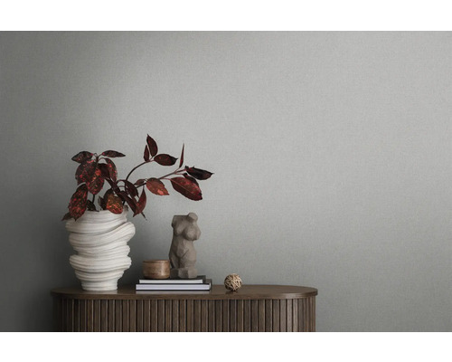 Nature morte décorative avec un vase de fleurs, des livres et un buste féminin sur une armoire en bois devant un mur gris