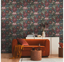 Salon avec papier peint à motif floral, canapé orange et tables en bois sur un tapis