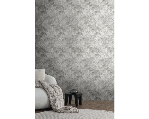 Salon avec papier peint à motifs de palmiers, fauteuil, couverture et table d''appoint.