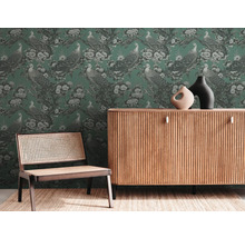 Salon avec papier peint vert à motif de paon, commode en bois et chaise avec cannage