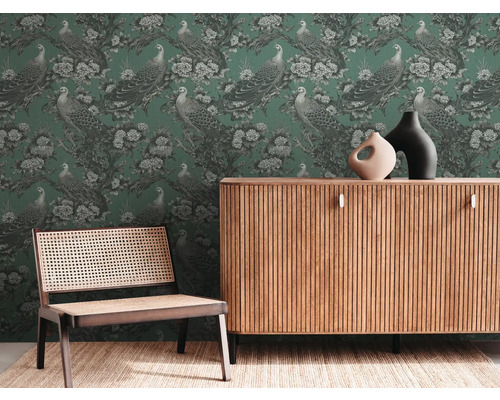 Salon avec papier peint vert à motif de paon, commode en bois et chaise avec cannage