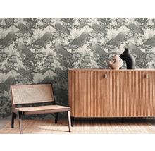 Pièce décorative avec un papier peint représentant des paons et des fleurs, une armoire en bois et une chaise en rotin.