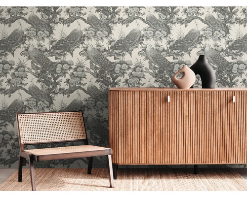 Pièce décorative avec un papier peint représentant des paons et des fleurs, une armoire en bois et une chaise en rotin.