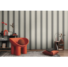 Espace aménagé avec papier peint à rayures, fauteuil et éléments décoratifs