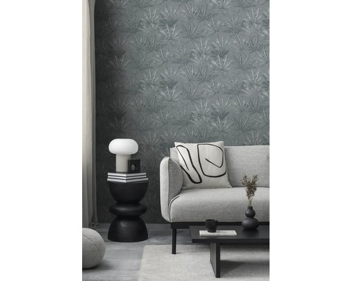 Salon avec papier peint à feuilles grises, canapé, table et décorations pour une ambiance élégante.