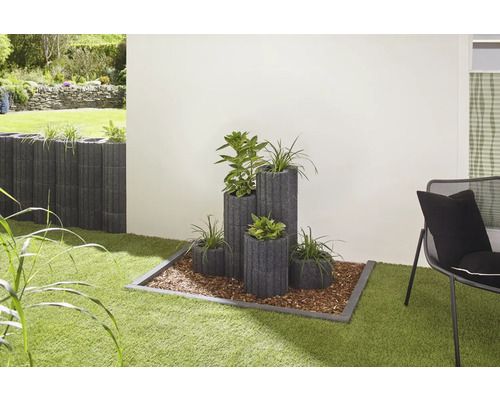 Scène de jardin avec des bacs à plantes de différentes tailles et des plantations sur une pelouse