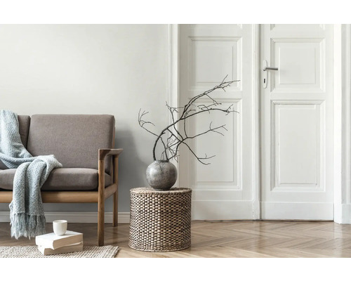 Salon avec canapé, table d''appoint en vannerie, vase avec des branches et pile de livres