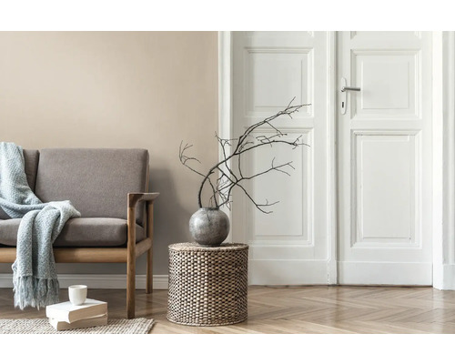 Salon avec canapé, table d''appoint en osier, vase avec des branches et porte en bois