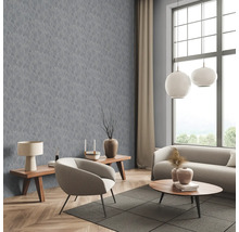 Salon avec papier peint gris à motif de feuilles, canapé, fauteuil et tables en bois.