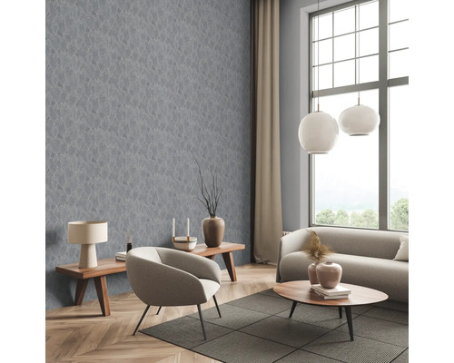 Salon avec papier peint gris à motif de feuilles, canapé, fauteuil et tables en bois.