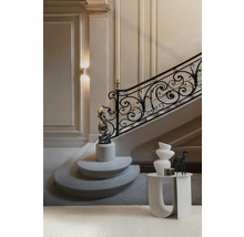 Elegantes Treppenhaus mit dekorativem Geländer und Skulpturen auf Podesten sowie einem Beistelltisch mit Vasen.