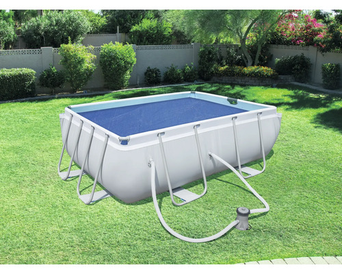 Piscine rectangulaire avec couverture et pompe de filtration dans le jardin.