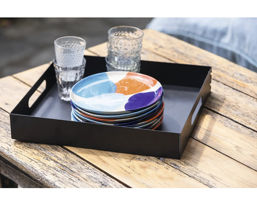 Plateau de service noir avec pile d''assiettes et verres sur une table en bois