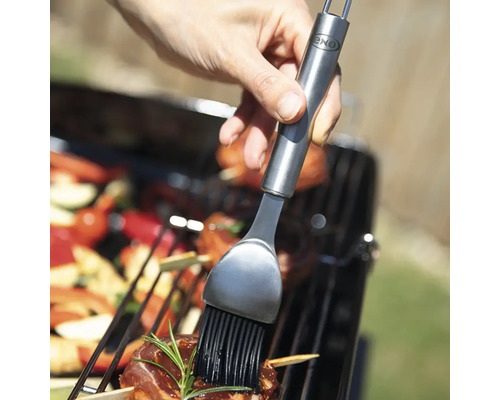 Une personne badigeonne des aliments grillés avec un pinceau de OXO