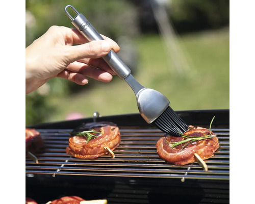 Pinceau à griller avec des aliments grillés sur une grille de barbecue